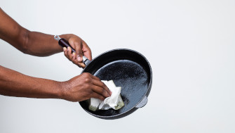 Bilden visar en hand som torkar ur en stekpanna med hushållspapper