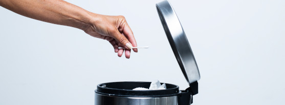 Bilden visar en hand som slänger sopor i en papperskorg. Skräpet täpper till ledningar, fastnar i pumpar och annan mekanisk utrustning och orsakar onödiga kostnader