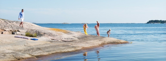 Bilden visar en familj som badar vid en häll i skärgård