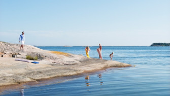 Bilden visar en familj som badar vid en häll i skärgård